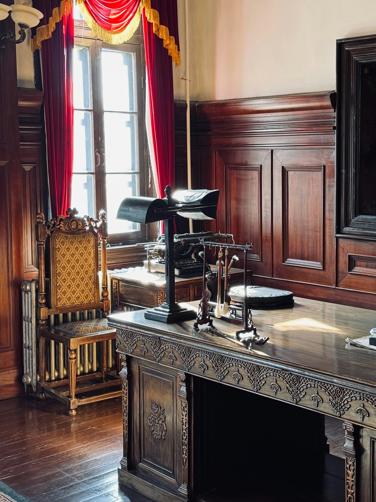 A carved desk by a window in a panelled study