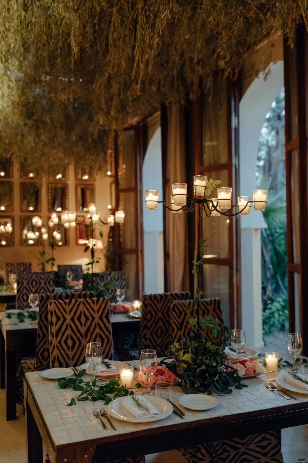 A small table set by candlelight in an arched courtyard, before the guests arrive