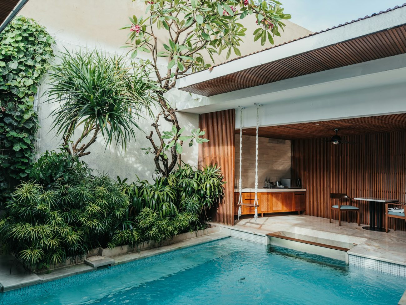 A modern house opening onto a pool and a tropical garden